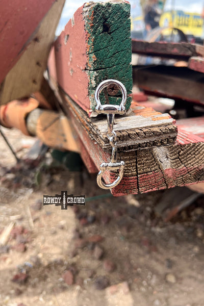 Metal clip attached to a wooden surface with 'Rowdy Crowd' branding.