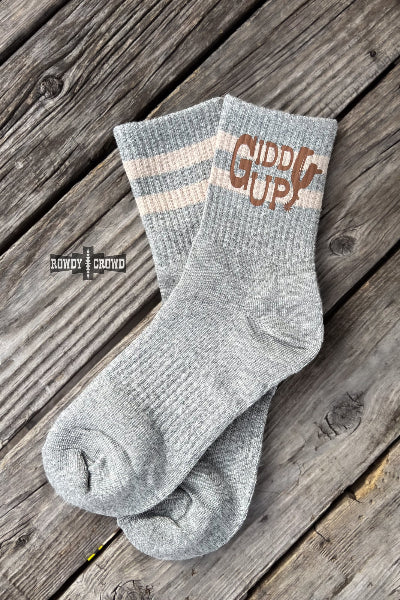 A pair of light gray heather crew socks with two cream stripes near the cuff and a brown 'CIPPUCCI' logo, displayed on a rustic wooden plank surface available at Cowtown Bling N Things.
