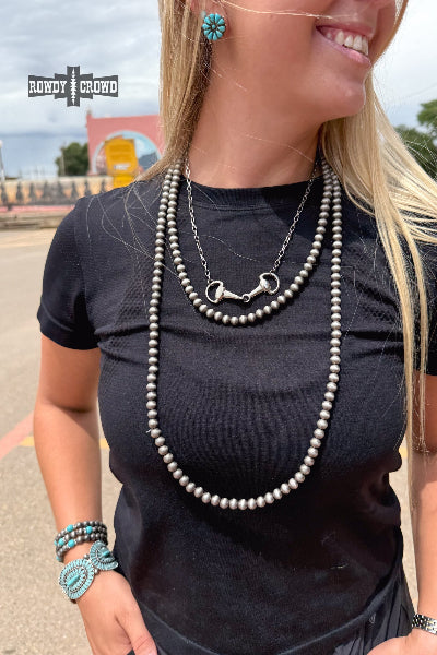 Woman wearing a black top with layered necklaces outdoors