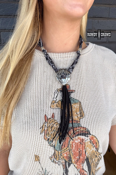 Person wearing a necklace with a horse and rider pendant on a graphic t-shirt.