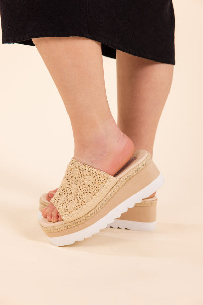 Beige platform sandals worn with a black skirt on a beige background