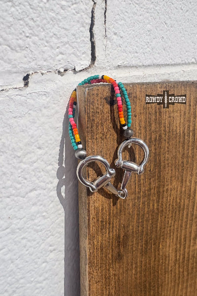 Rowdy Crowd Clothing SHOWROOM - Sunset Bit Bracelet is a colorful beaded keychain with metal hooks on a wooden block against a textured wall available at Cowtown Bling N Things.