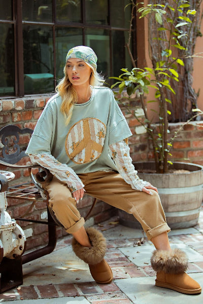Easel Lace Peace Patch Top worn by woman seated on bench.
