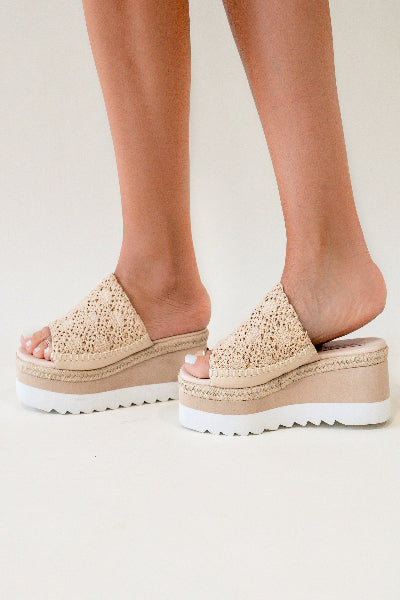 Beige espadrille sandals with platform sole worn by a person on a light background