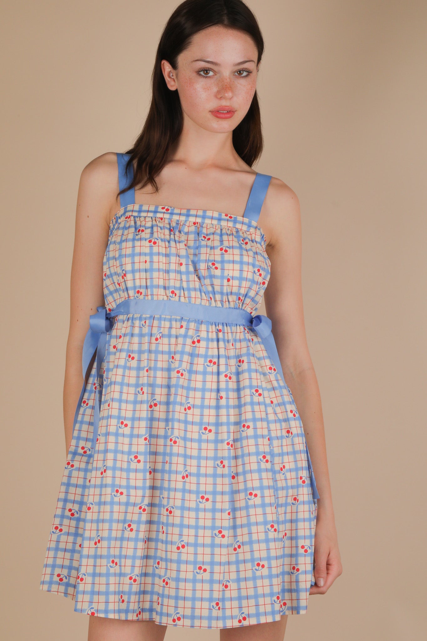 Woman wearing a blue checkered dress with floral patterns on a beige background