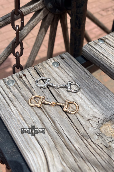 Two horse bits on a wooden surface with 'Randy & Crow' branding.