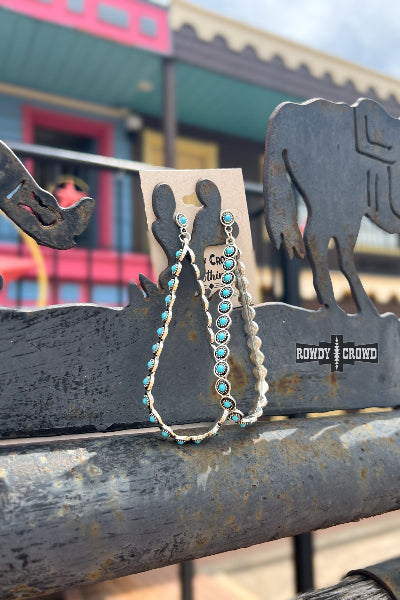 Bracelets with turquoise stones on a display card, placed on a metal surface with 'Rowdy Crowd' branding.