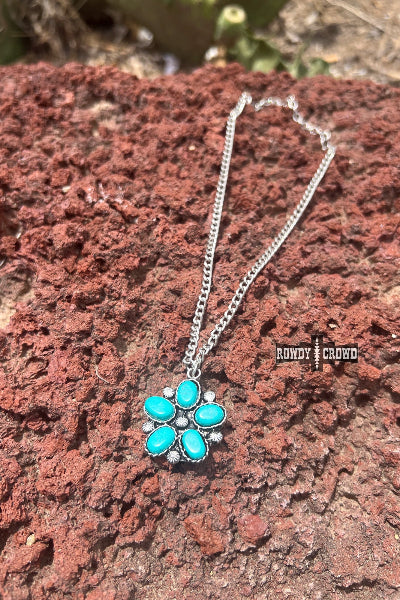 Necklace with turquoise flower pendant on a red rock background