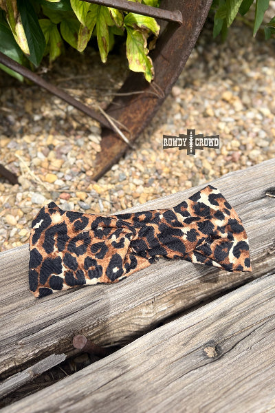 Leopard print bow tie on a wooden surface with 'Rowdy & Refined' branding.