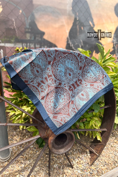Patterned blanket on a rustic wheel with 'Rowdy & Rodeo' branding in the background.