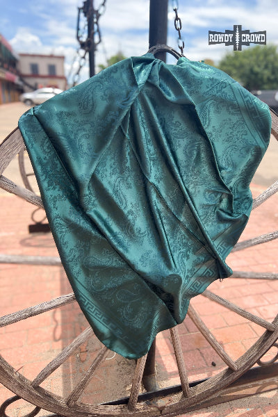 Teal patterned fabric draped over a wooden wheel with a blurred background