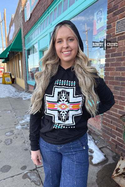 Woman wearing a black hoodie with a graphic design on a city street.