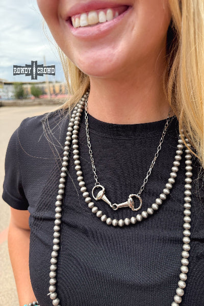 Woman wearing a necklace with a horse bit charm, with 'Bundy & Cord' branding in the background.