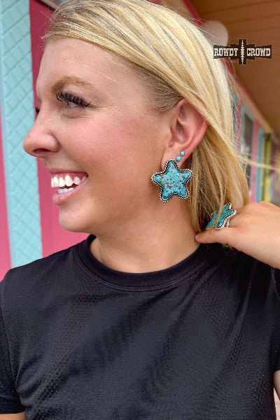 Woman wearing turquoise star-shaped earrings with a colorful background