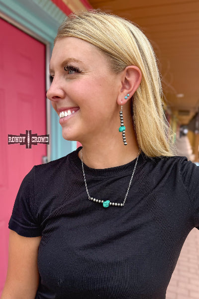 Woman wearing earrings and a necklace with a blurred background