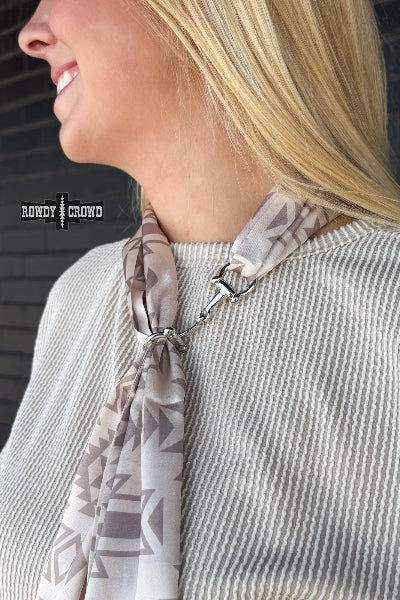 Woman wearing a patterned scarf around her neck with 'Rowdy & Rund' branding.