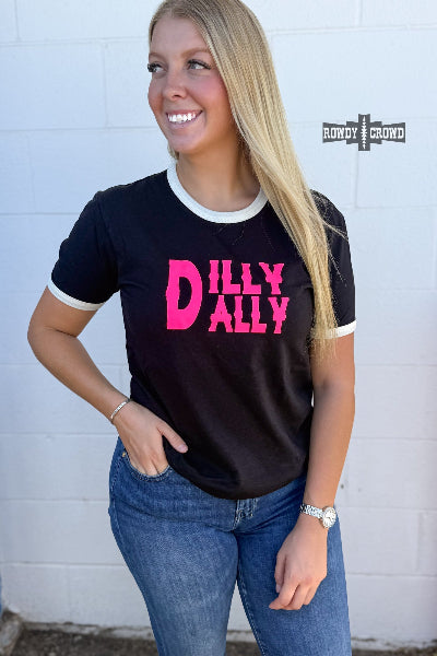 A woman wearing a black ringer t-shirt with pink and white lettering that reads 'DILLY ALLEY' stands against a white brick wall. The brand logo 'BONITO CLOTHING' is visible on the wall.