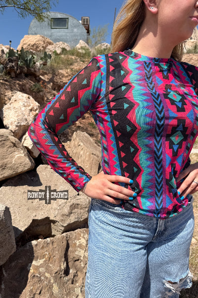 Person wearing a colorful patterned shirt with a desert landscape in the background