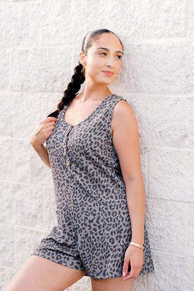Woman wearing a leopard print romper against a textured white wall