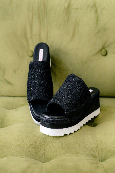 Black glittery sandals on a green cushion