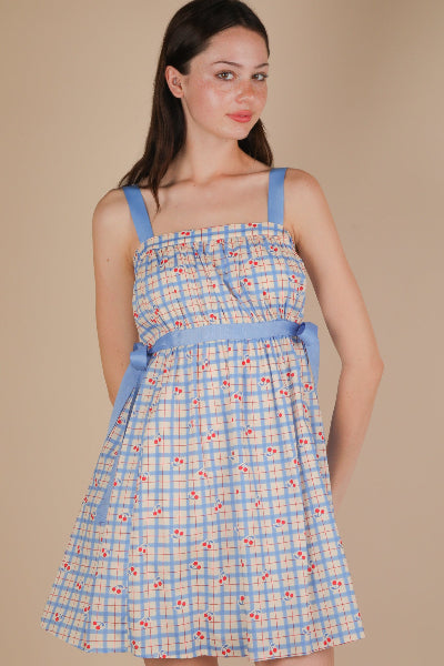 Woman wearing a blue and yellow checkered dress with floral pattern on a beige background